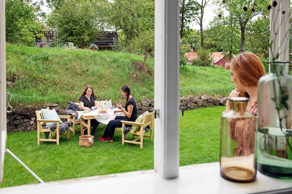 Trädgård med flera sittgrupper och vackra planteringar