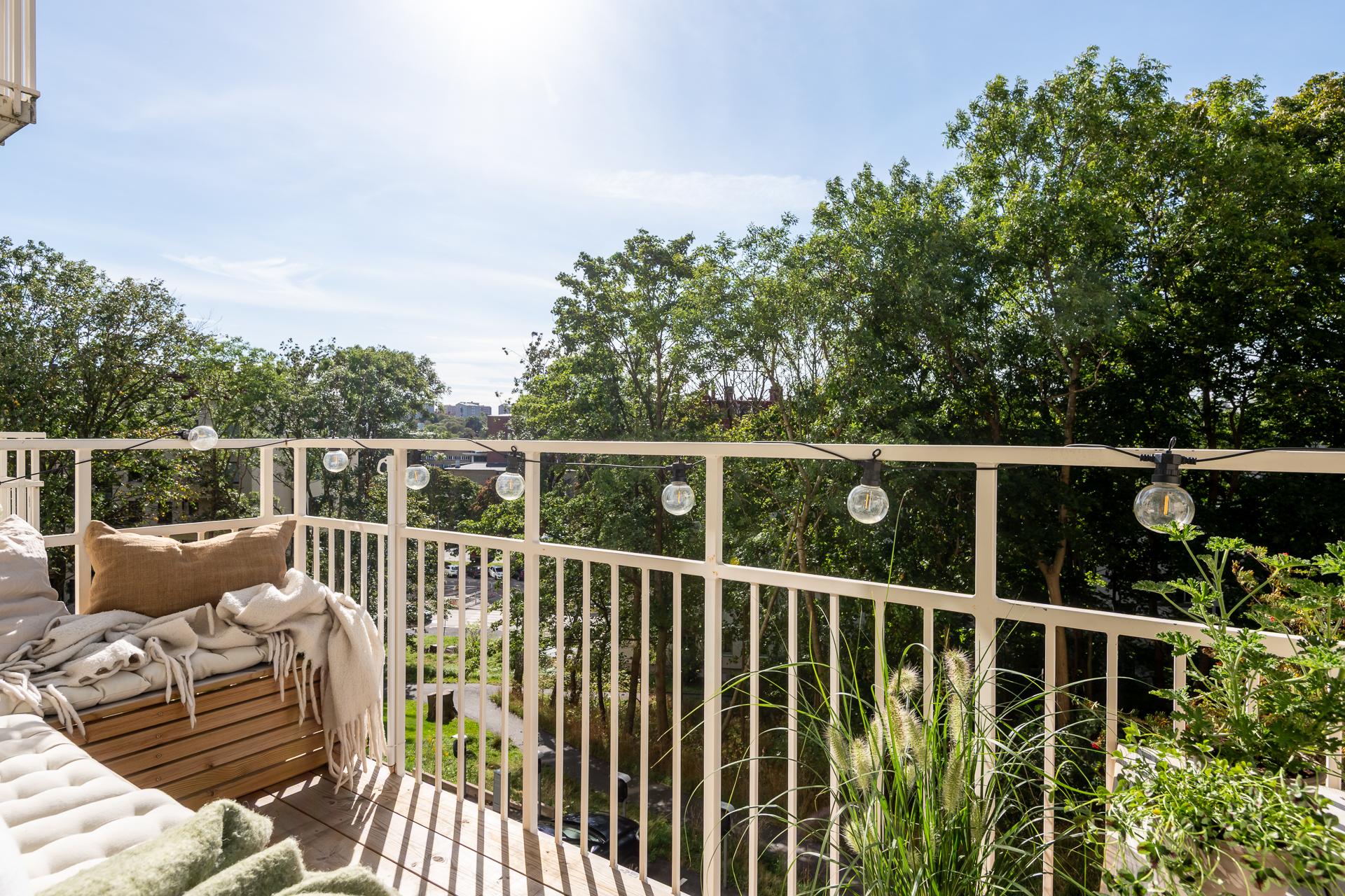 Stor västervänd balkong med platsbyggd bänk