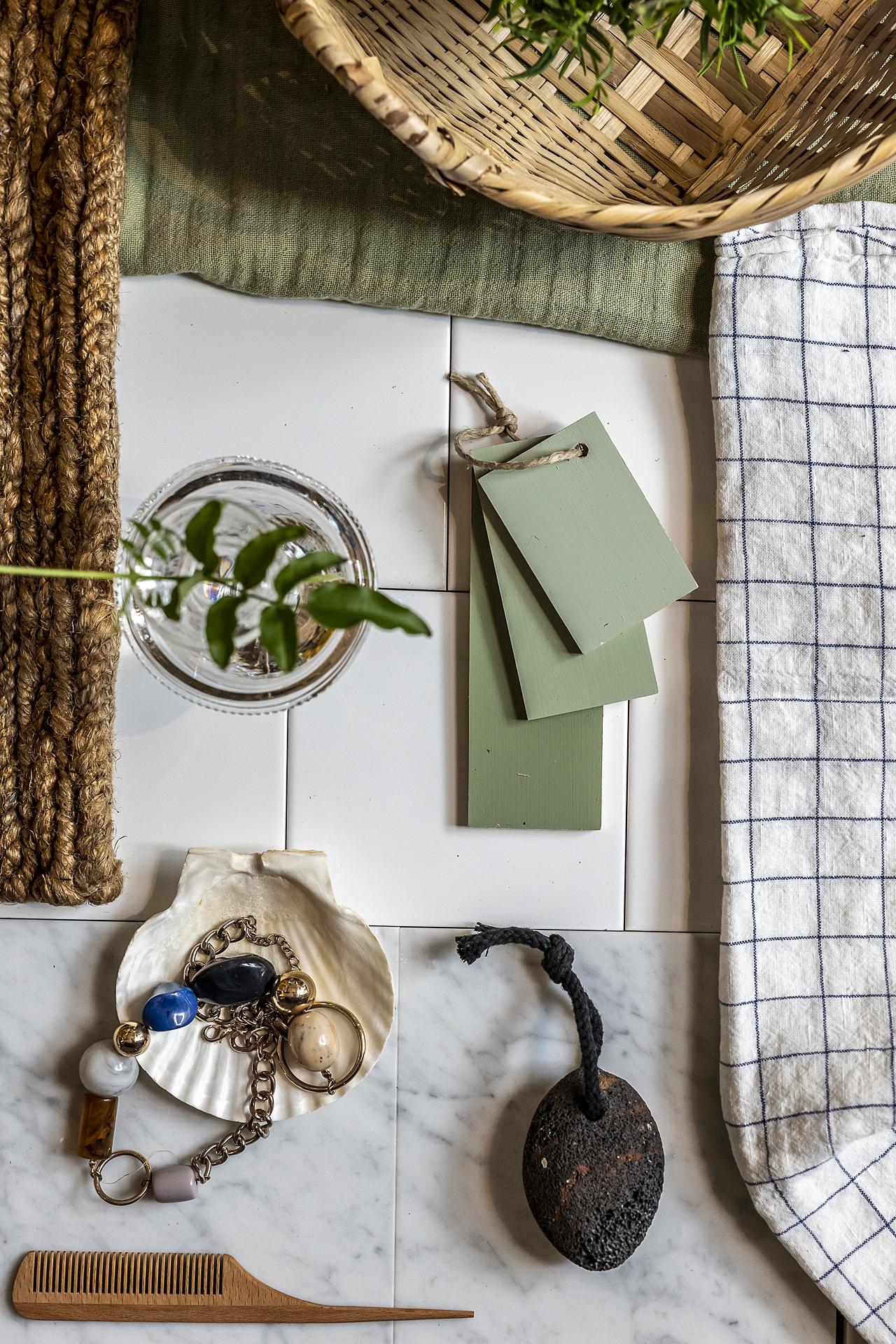 Badrummet har klassisk marmor på golvet, halvkaklade väggar i vitt mot lindblomsgrön väggfärg