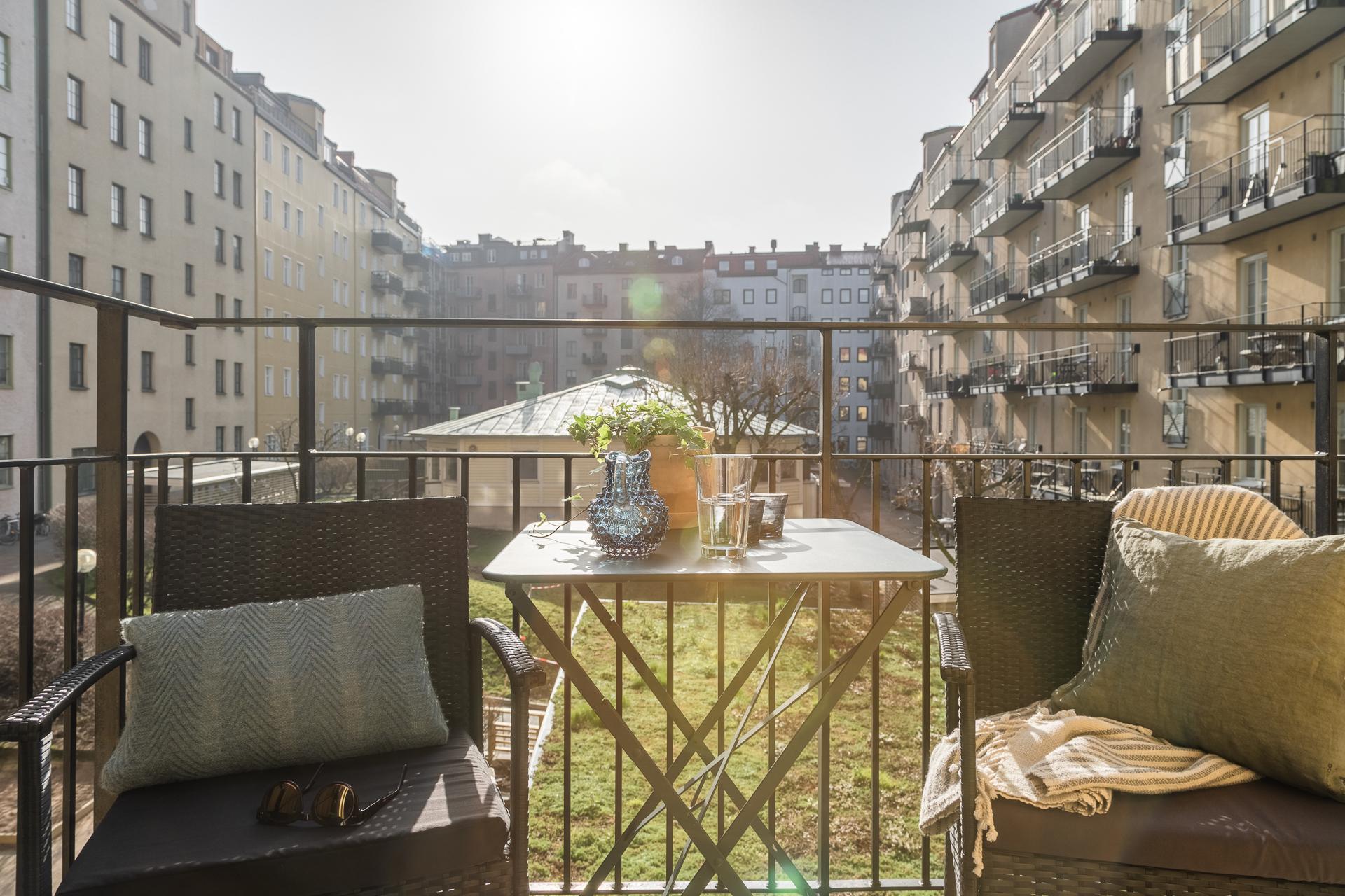 Soldränkt balkong mot en öppen grön innergård